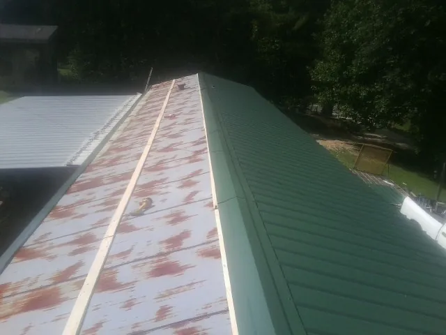 Old rusted panels beside newly installed green metal roofing — Wind Damage Roof Repair by Roofing Brothers in Hyannis