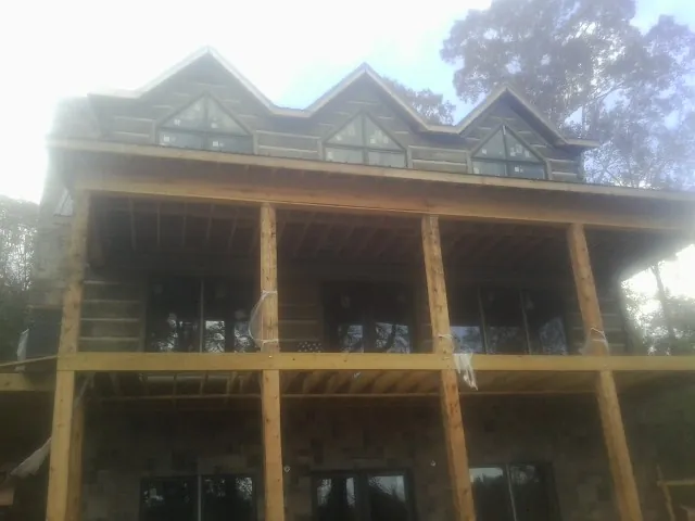 Dormers and porch framing on a large log home under construction — Roof Coating work by our crew in Hyannis