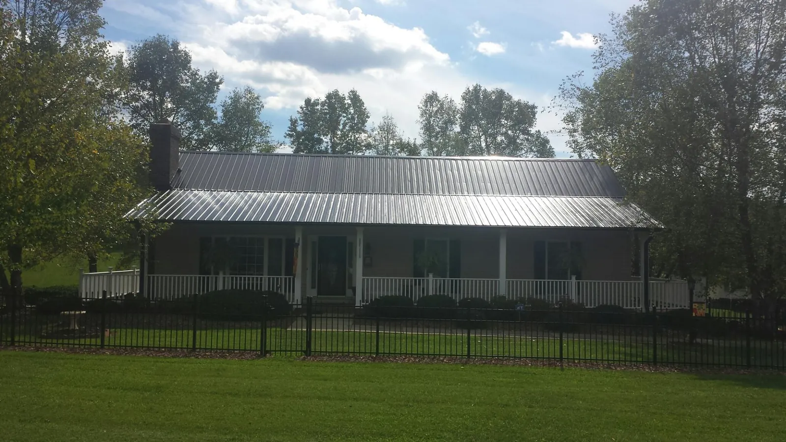 Gray metal roof on a brick ranch with a full width front porch — Gutter Guard Installation work by our crew in Hyannis