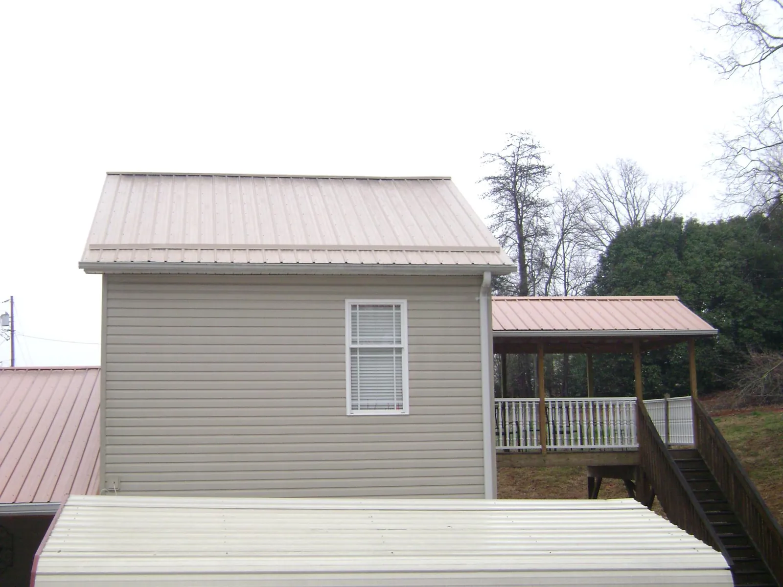 Tan metal roofs on a two story addition and attached porch, from a Roof Replacement job in Hyannis